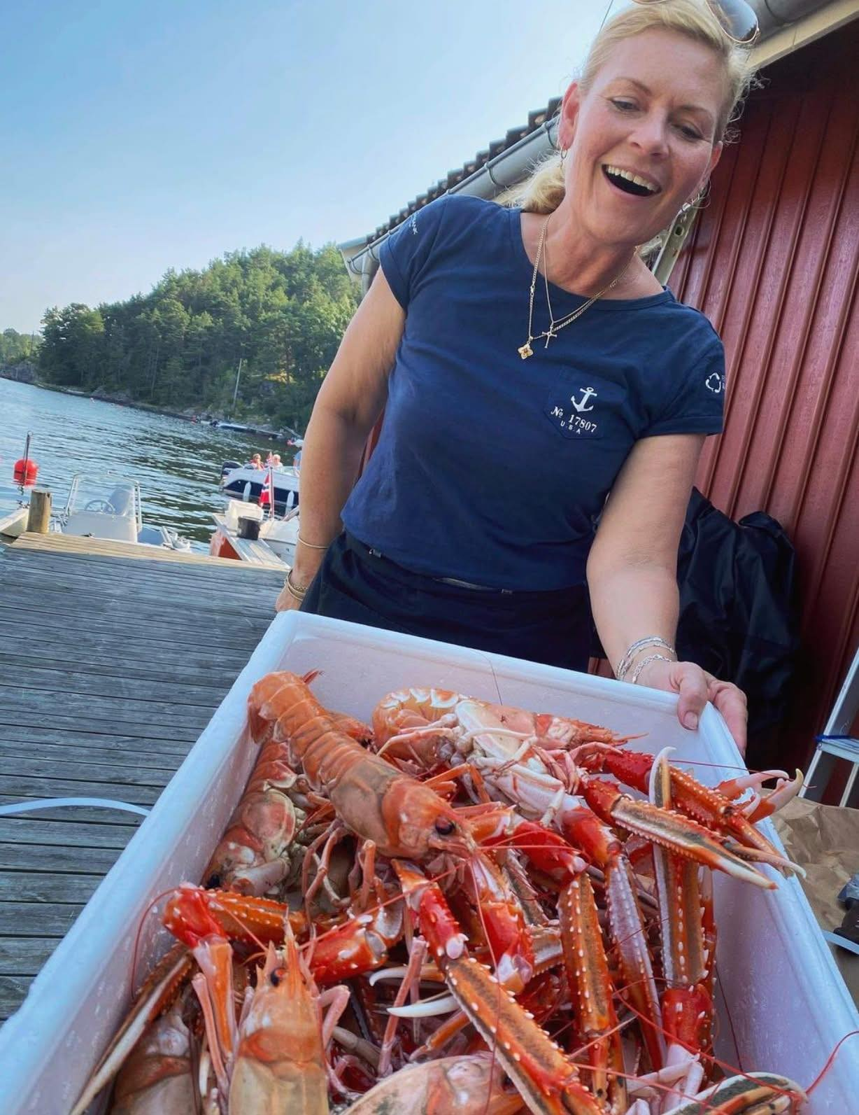 Smilende vertinne fra Sjøbua i Sponvika viser frem ferske sjøkreps på bryggekanten – førsteklasses skalldyr ved Ringdalsfjorden