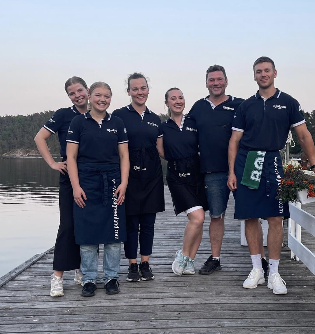 Sjøbua-teamet samlet på brygga i Sponvika – dedikerte medarbeidere i uniform foran Ringdalsfjorden nær Halden