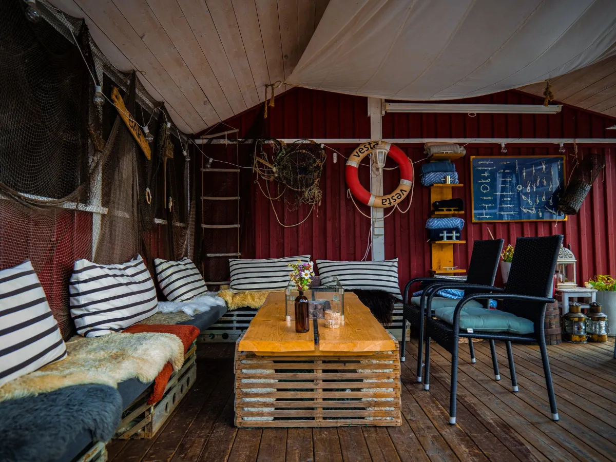 Idyllisk terrasse på Sjøbua i Sponvika med komfortable loungemøbler og maritim stemning – perfekt for avslappende måltider ved Ringdalsfjorden nær Halden